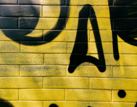 a yellow brick wall with black graffiti on it