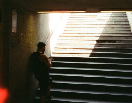 Man contemplates stairs in a dim subway tunnel.